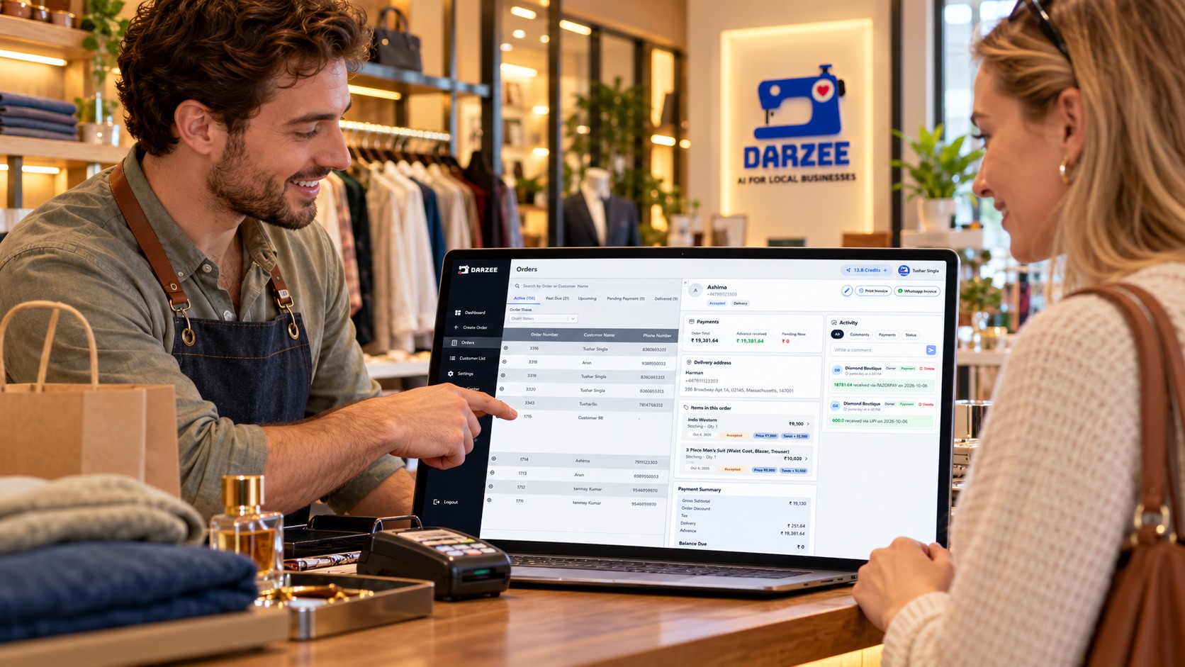 A shop assistant and customer reviewing a Darzee order on a laptop at a retail checkout counter.